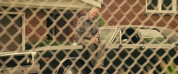 Movie still from “Cold in July” (2014), directed by Jim Mickle – An older man sitting on the hood of a car; Medium shot, Low angle