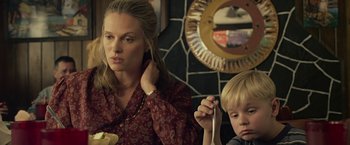 Movie still from “Cold in July” (2014), directed by Jim Mickle – A woman sitting next to a boy in a room; Close Up shot, Over the shoulder angle