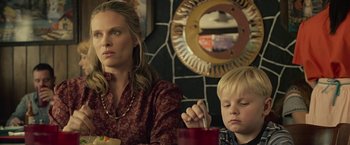 Movie still from “Cold in July” (2014), directed by Jim Mickle – A woman sitting next to a boy at a table; Close Up shot, Over the shoulder angle
