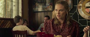 Movie still from “Cold in July” (2014), directed by Jim Mickle – A woman sitting at a table with a plate in front of her; Close Up shot, Over the shoulder angle