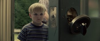 Movie still from “Cold in July” (2014), directed by Jim Mickle – A young boy standing in front of an open door; Close Up shot, Over the shoulder angle