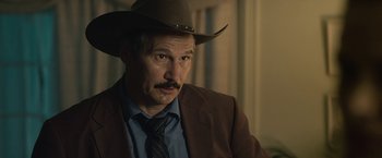 Movie still from “Cold in July” (2014), directed by Jim Mickle – A man in a brown jacket and a brown cowboy hat; Close Up shot, Over the shoulder angle