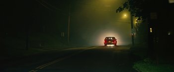 Movie still from “Cold in July” (2014), directed by Jim Mickle – A car driving down a street at night with fog; Extreme Wide shot, High angle