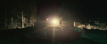 Movie still from “Cold in July” (2014), directed by Jim Mickle – A man is standing on a train track in the dark; Extreme Wide shot, Low angle