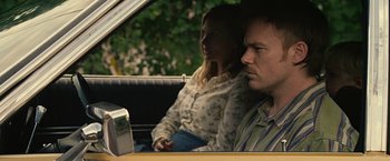 Movie still from “Cold in July” (2014), directed by Jim Mickle – A man and a woman sitting in the back of a car; Medium shot, Over the shoulder angle