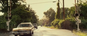 Movie still from “Cold in July” (2014), directed by Jim Mickle – Cars driving down a street with power lines overhead; Extreme Wide shot, Low angle