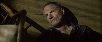 Movie still from “Cold in July” (2014), directed by Jim Mickle – An older man with a goatee looking at the camera; Close Up shot, Low angle