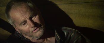 Movie still from “Cold in July” (2014), directed by Jim Mickle – A man's face in the dark; Close Up shot, Over the shoulder angle