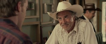 Movie still from “Cold in July” (2014), directed by Jim Mickle – An older man wearing a white cowboy hat; Close Up shot, Over the shoulder angle