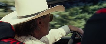 Movie still from “Cold in July” (2014), directed by Jim Mickle – An older man wearing a cowboy hat driving a car; Close Up shot, Over the shoulder angle