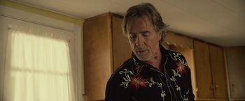 Movie still from “Cold in July” (2014), directed by Jim Mickle – An older man in a black shirt is looking down; Close Up shot, Over the shoulder angle