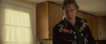 Movie still from “Cold in July” (2014), directed by Jim Mickle – A man standing in front of a kitchen counter; Medium shot, Over the shoulder angle