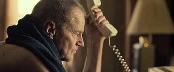 Movie still from “Cold in July” (2014), directed by Jim Mickle – An older man holding up a white telephone; Close Up shot, Low angle