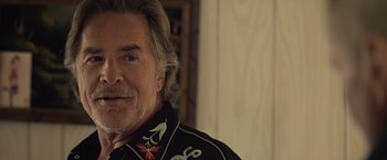 Movie still from “Cold in July” (2014), directed by Jim Mickle – An older man with long gray hair wearing a black shirt; Close Up shot, Over the shoulder angle