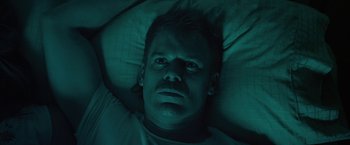 Movie still from “Cold in July” (2014), directed by Jim Mickle – A man laying in a bed under a blanket; Close Up shot, Overhead angle