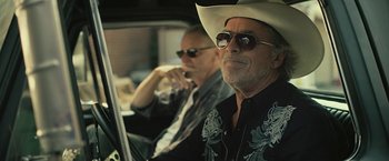 Movie still from “Cold in July” (2014), directed by Jim Mickle – A man in a cowboy hat sitting next to another man; Close Up shot, Low angle