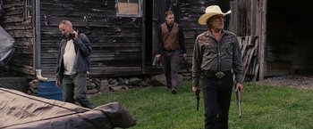 Movie still from “Cold in July” (2014), directed by Jim Mickle – Two men in cowboy hats are walking in a field; Medium shot, Over the shoulder angle
