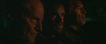 Movie still from “Cold in July” (2014), directed by Jim Mickle – Two men in a dimly - lit room looking at the camera; Close Up shot, Over the shoulder angle