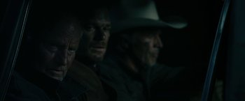 Movie still from “Cold in July” (2014), directed by Jim Mickle – A man in a cowboy hat sitting next to another man; Close Up shot, Over the shoulder angle