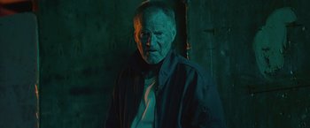 Movie still from “Cold in July” (2014), directed by Jim Mickle – An older man in a dark room looking at the camera; Close Up shot, Low angle