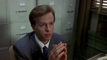 Movie still from “Coneheads” (1993), directed by Steve Barron – A person wearing a suit clapping his hands; Close Up shot, Over the shoulder angle