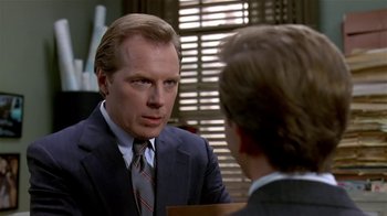 Movie still from “Coneheads” (1993), directed by Steve Barron – A man wearing a suit and tie talking to another man in a suit; Close Up shot, Over the shoulder angle