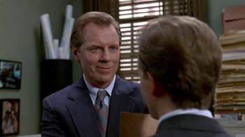 Movie still from “Coneheads” (1993), directed by Steve Barron – A man wearing a suit and tie talking to another man in a suit and tie; Close Up shot, Over the shoulder angle