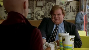 Movie still from “Coneheads” (1993), directed by Steve Barron – A man sitting at a table in front of another man; Medium shot, Over the shoulder angle