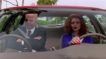 Movie still from “Coneheads” (1993), directed by Steve Barron – A man and a woman sitting in the back seat of a car; Medium shot, Over the shoulder angle