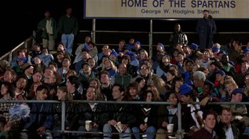 Movie still from “Coneheads” (1993), directed by Steve Barron – A group of people sitting on top of bleachers at a sporting event; Wide shot, High angle