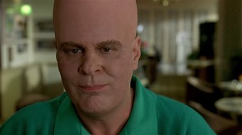 Movie still from “Coneheads” (1993), directed by Steve Barron – A man with a bald head is looking at the camera; Close Up shot, Low angle