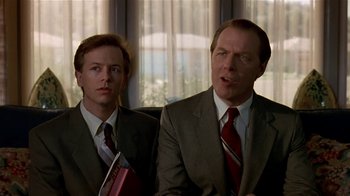 Movie still from “Coneheads” (1993), directed by Steve Barron – A man and a man in a suit and tie; Close Up shot, Low angle