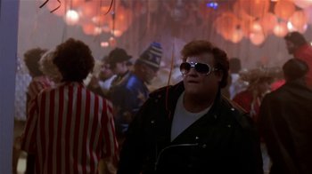 Movie still from “Coneheads” (1993), directed by Steve Barron – A man in a black jacket and sunglasses; Medium shot, Over the shoulder angle