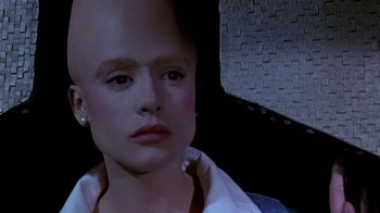Movie still from “Coneheads” (1993), directed by Steve Barron – A young woman with a bald head sitting in a car; Close Up shot, High angle