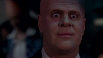 Movie still from “Coneheads” (1993), directed by Steve Barron – A bald man wearing a suit and tie; Close Up shot, Low angle