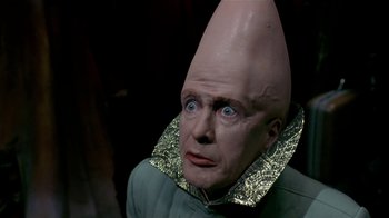 Movie still from “Coneheads” (1993), directed by Steve Barron – A man with a large head wearing a cone hat; Close Up shot, High angle