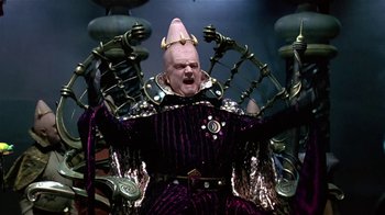 Movie still from “Coneheads” (1993), directed by Steve Barron – A man in a purple suit and a pink hat; Medium shot, Low angle