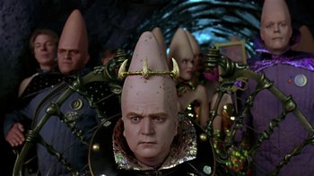 Movie still from “Coneheads” (1993), directed by Steve Barron – A person wearing a strange hat; Medium shot, Low angle