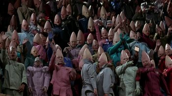Movie still from “Coneheads” (1993), directed by Steve Barron – A group of people wearing odd clothes and hats in a crowd; Extreme Wide shot, High angle