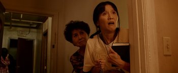 Movie still from “Constantine” (2005), directed by Francis Lawrence – Two women in a room with one holding a phone and the other holding a book; Medium shot, Low angle