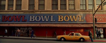 Movie still from “Constantine” (2005), directed by Francis Lawrence – People walk on the sidewalk in front of a bowl bowl restaurant; Extreme Wide shot, High angle