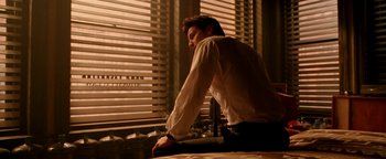 Movie still from “Constantine” (2005), directed by Francis Lawrence – A man sitting at a table in front of a window; Medium shot, Low angle