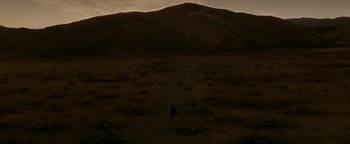 Movie still from “Constantine” (2005), directed by Francis Lawrence – A person walking down a dirt road near a mountain; Extreme Wide shot, High angle