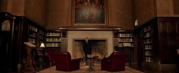 Movie still from “Constantine” (2005), directed by Francis Lawrence – A man standing in front of a fireplace in a room; Wide shot, Low angle