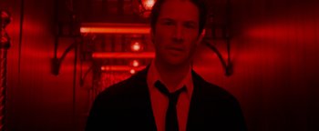Movie still from “Constantine” (2005), directed by Francis Lawrence – A man wearing a suit and tie standing in front of a red background; Close Up shot, Low angle