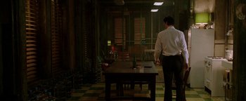Movie still from “Constantine” (2005), directed by Francis Lawrence – A man standing at a table in a dark room; Wide shot, Over the shoulder angle