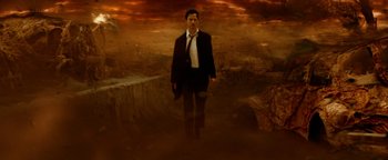 Movie still from “Constantine” (2005), directed by Francis Lawrence – A man in a suit and tie standing in front of a cliff; Wide shot, Low angle