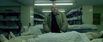 Movie still from “Constantine” (2005), directed by Francis Lawrence – A man standing in a room with a bunch of beds; Medium shot, Low angle