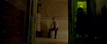 Movie still from “Constantine” (2005), directed by Francis Lawrence – A man sitting on the edge of a bathtub in a bathroom; Wide shot, Low angle