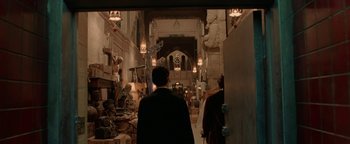 Movie still from “Constantine” (2005), directed by Francis Lawrence – A man walking through an indoor area with statues and sculptures; Wide shot, Over the shoulder angle